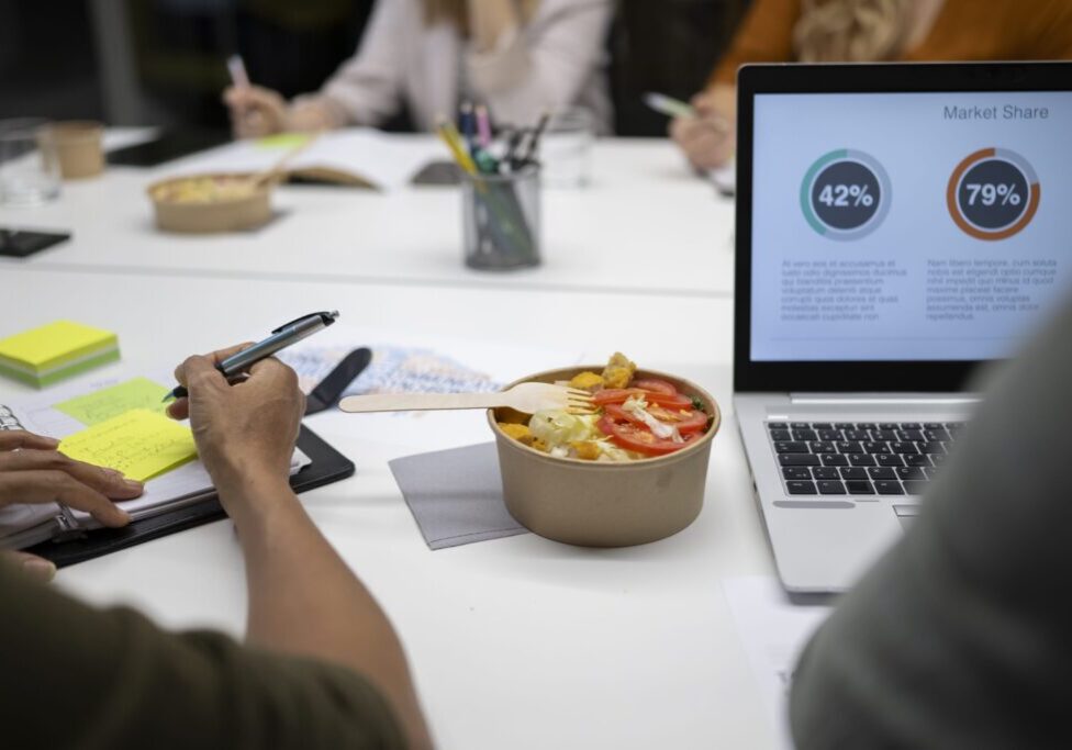 Meeting table with laptop and salad bowl.