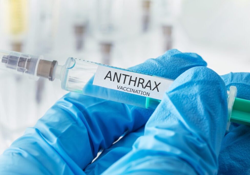 Anthrax vaccination syringe held with gloves.